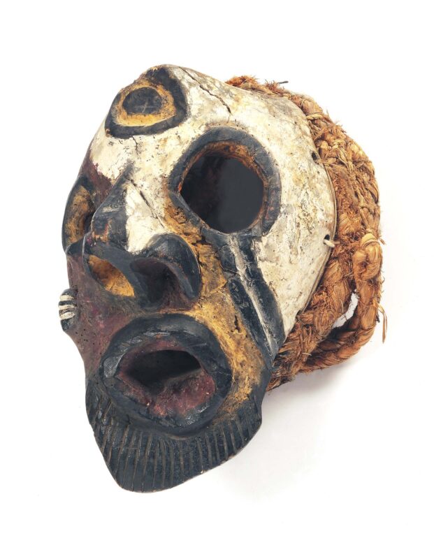 Mask with facial distortion made with wood with red, white, and black pigments, raffia.