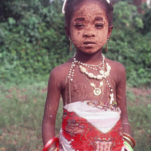 thumbnail of A child with yellow markings, jewelry and red and white clothing