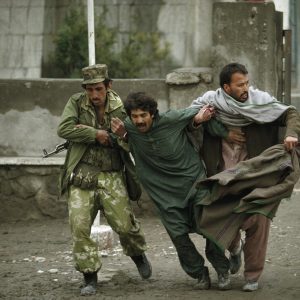 thumbnail of MARCH 1993: Two Afghans help a wounded civilian through cross fire during a battle between rival factions in Kabul.