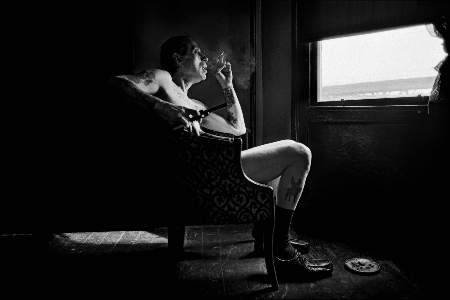thumbnail of Uncle Charlie contemplating in his living room the reality that his son Joe is dying from HIV, sitting by the window holding his newest and latest handgun in his apartment in Bushwick, Brooklyn in 1996.