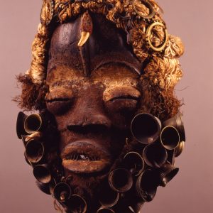 thumbnail of Mask with multiple materials from Liberia/Ivory Coast. medium: brass, textile, animal tooth. date: unknown. height: 12 inches