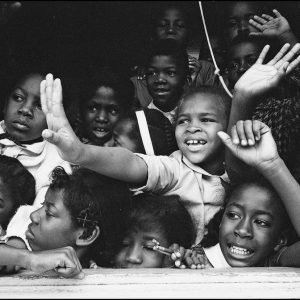 thumbnail of Grade School Children waving to Dr. King and Civil Rights Leaders by Dan Budnik. medium: silver gelatin print. date: March, 1965. dimensions: 8.25 x 12 inches